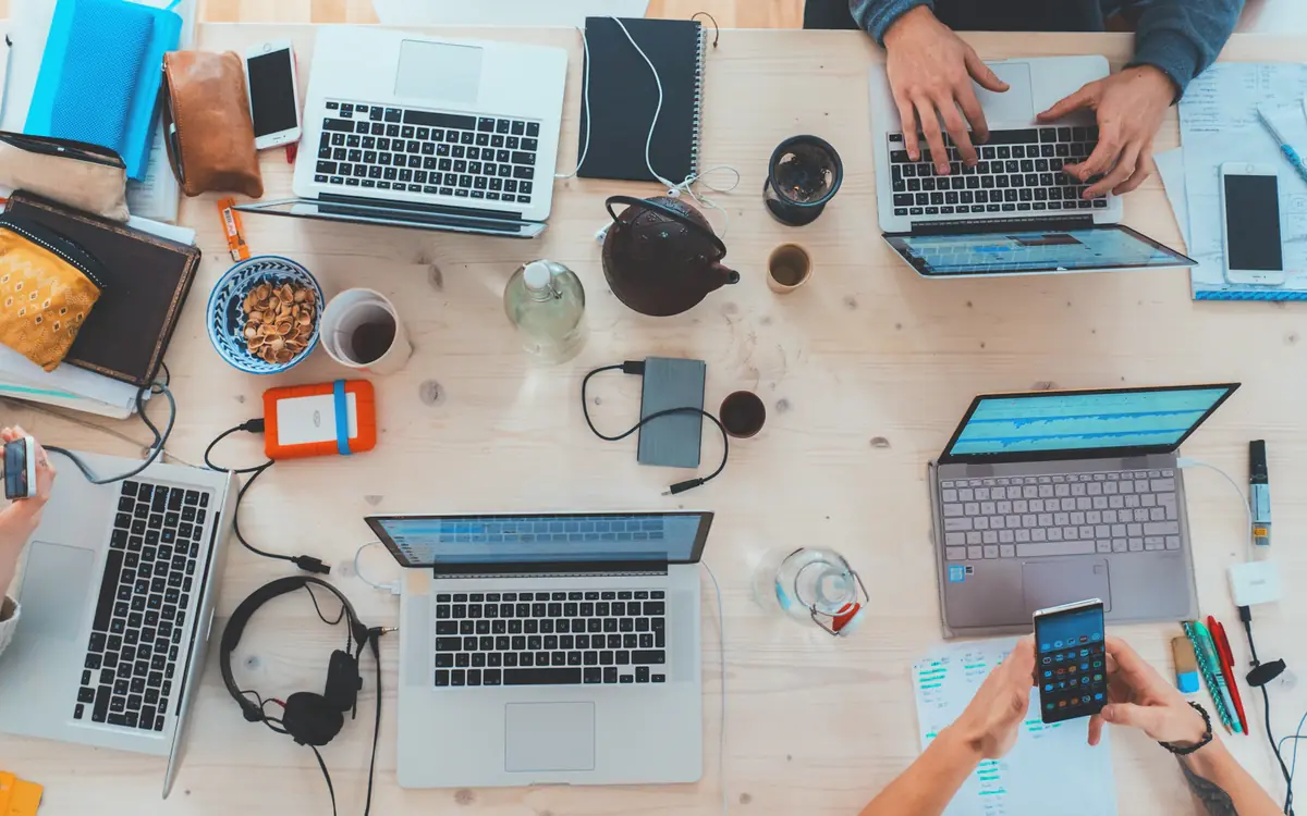 Writers, marketers and developers working on laptops around one table