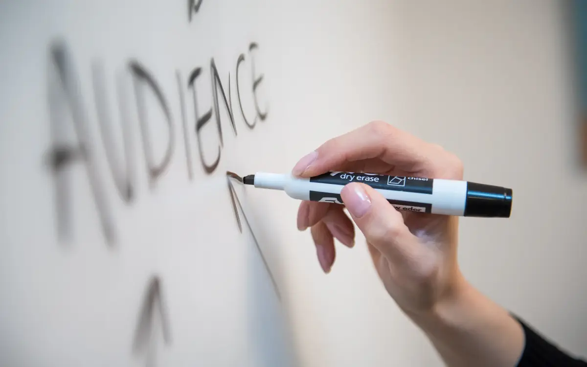 About Us 5 Marketer writing the word audience on a whiteboard while planning content