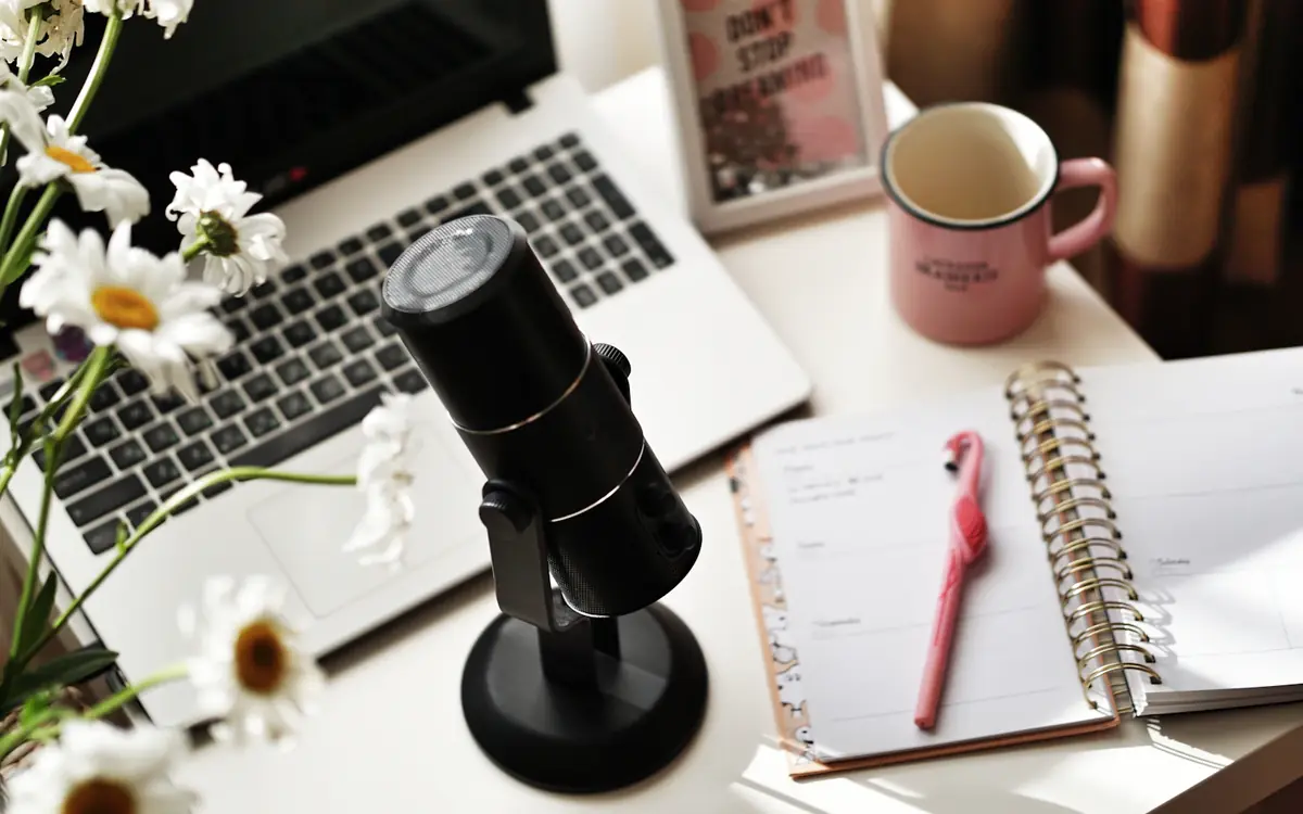 Blog writing desk with a laptop, notebook, microphone and coffee mug