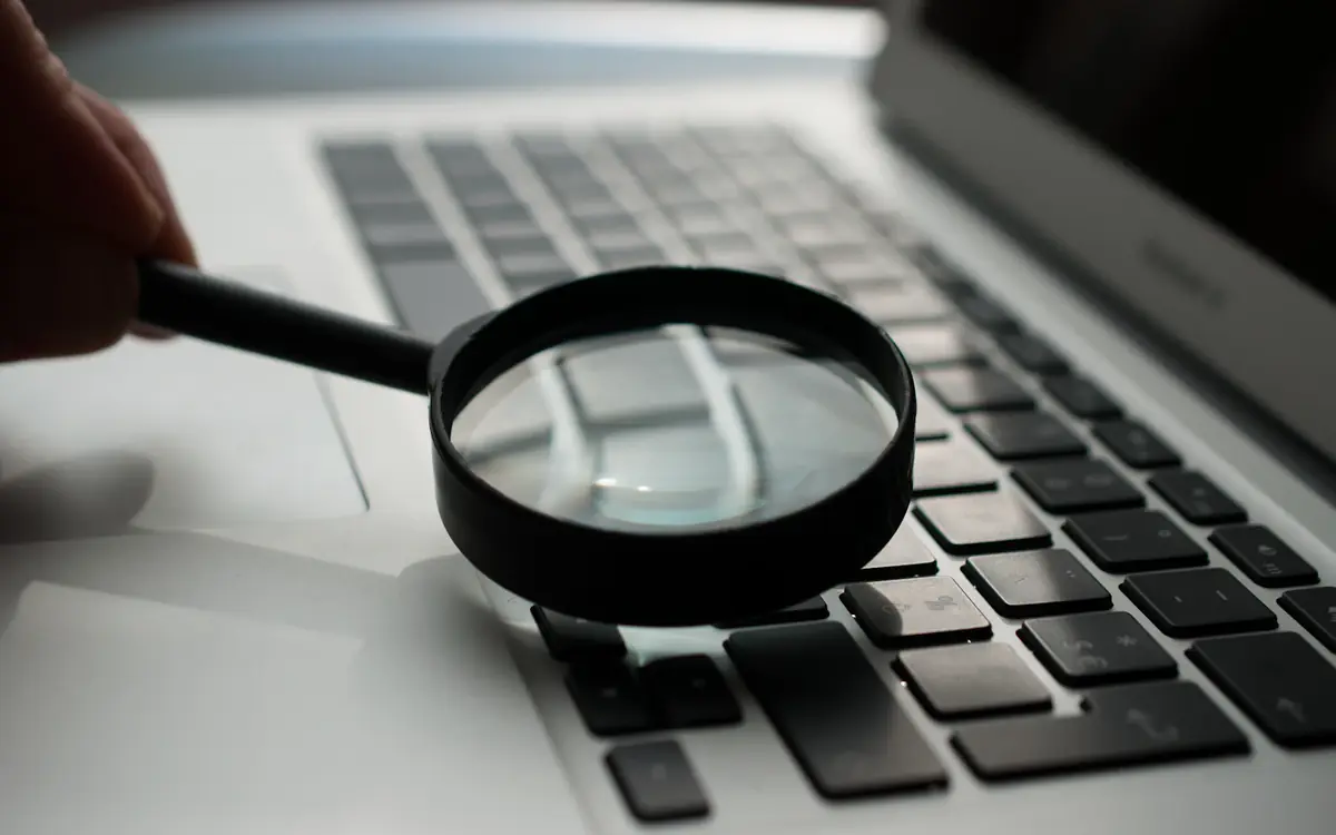 Magnifying glass on a laptop keyboard, showing a close website audit